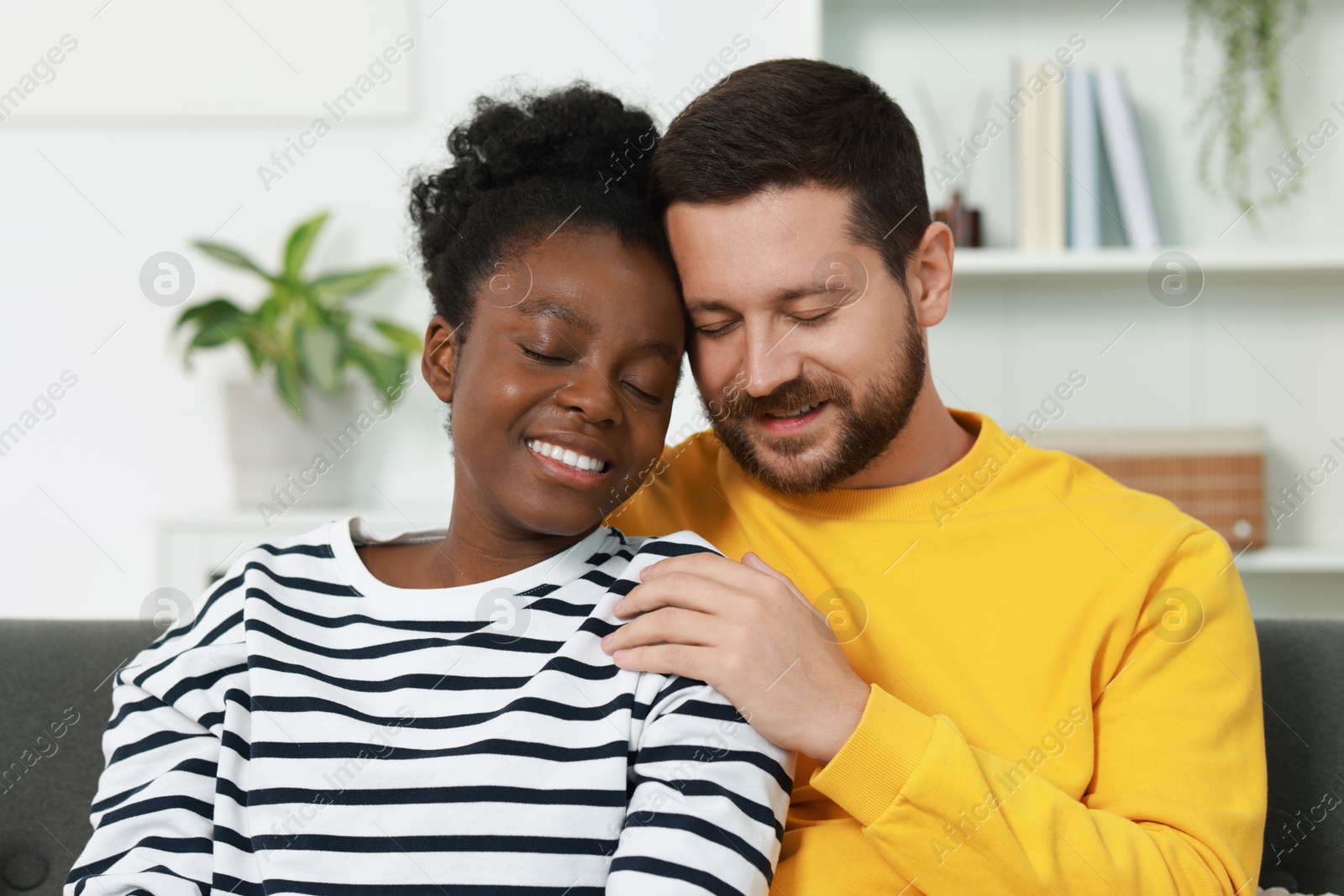 Photo of International relationships. Portrait of lovely couple on sofa at home