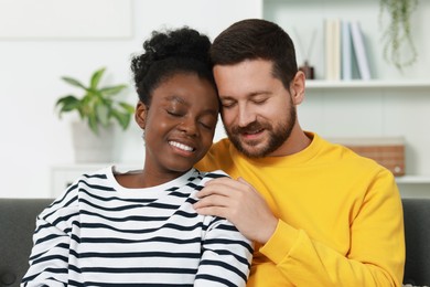 International relationships. Portrait of lovely couple on sofa at home