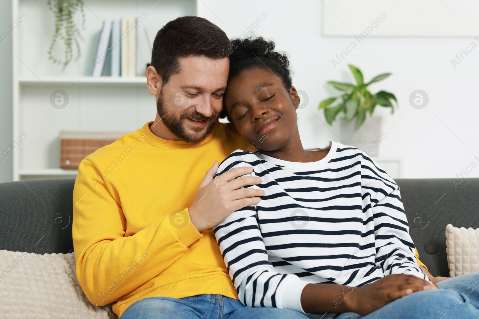 Photo of International relationships. Portrait of lovely couple on sofa at home