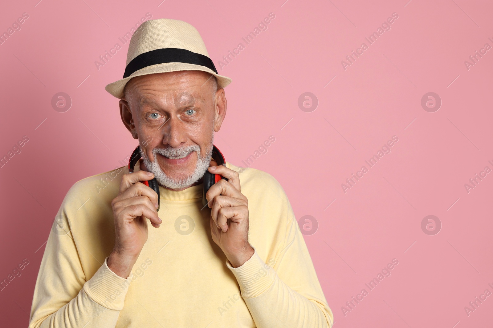 Photo of Portrait of handsome senior man with headphones on pink background. Space for text