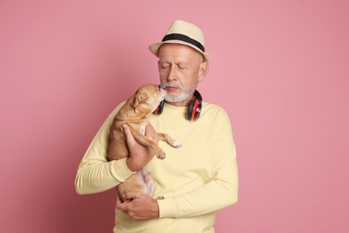 Portrait of handsome senior man with Chihuahua dog on pink background