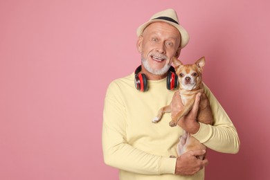 Portrait of happy senior man with Chihuahua dog on pink background. Space for text