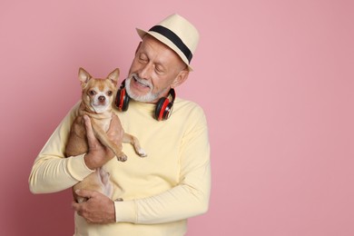 Portrait of handsome senior man with Chihuahua dog on pink background. Space for text