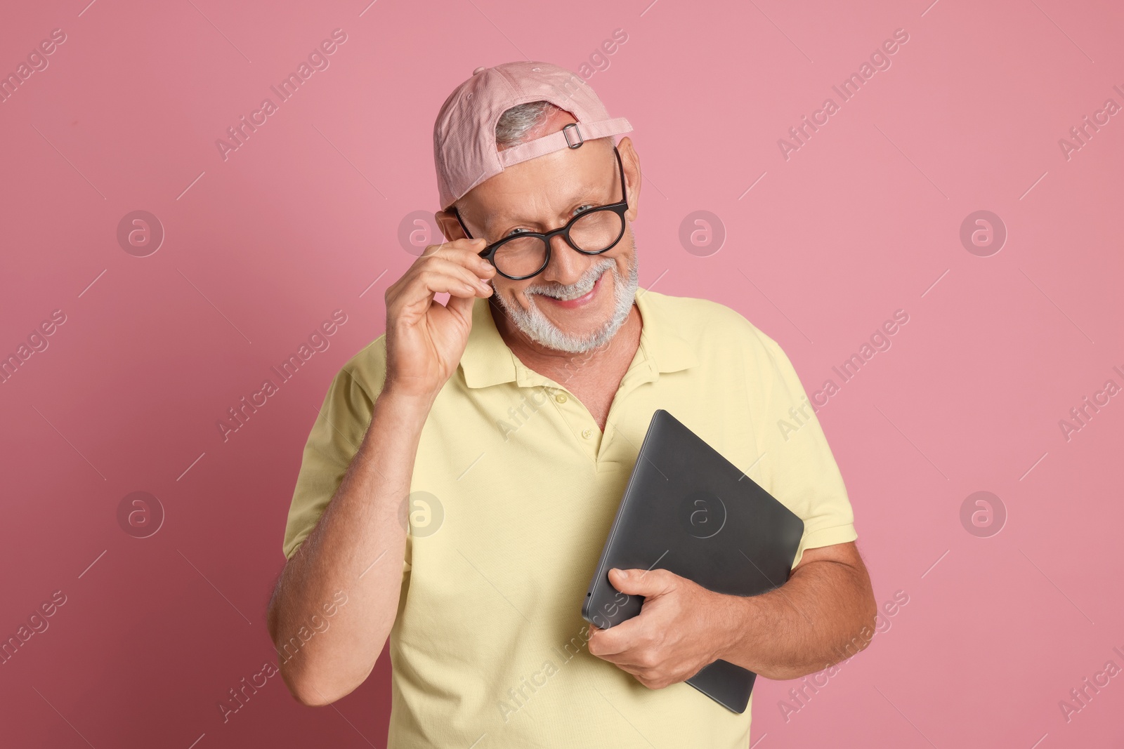 Photo of Portrait of handsome senior man with laptop on pink background