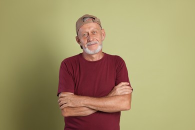 Portrait of senior man with crossed arms on green background