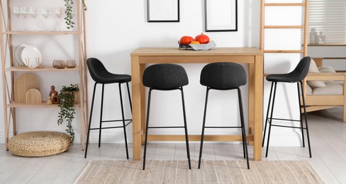 Photo of Bar stools near wooden table in room