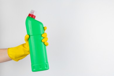 Photo of Woman holding toilet cleaner in bottle on light background, closeup. Space for text