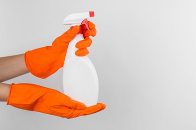 Photo of Woman holding toilet cleaner in spray bottle on light background, closeup. Space for text