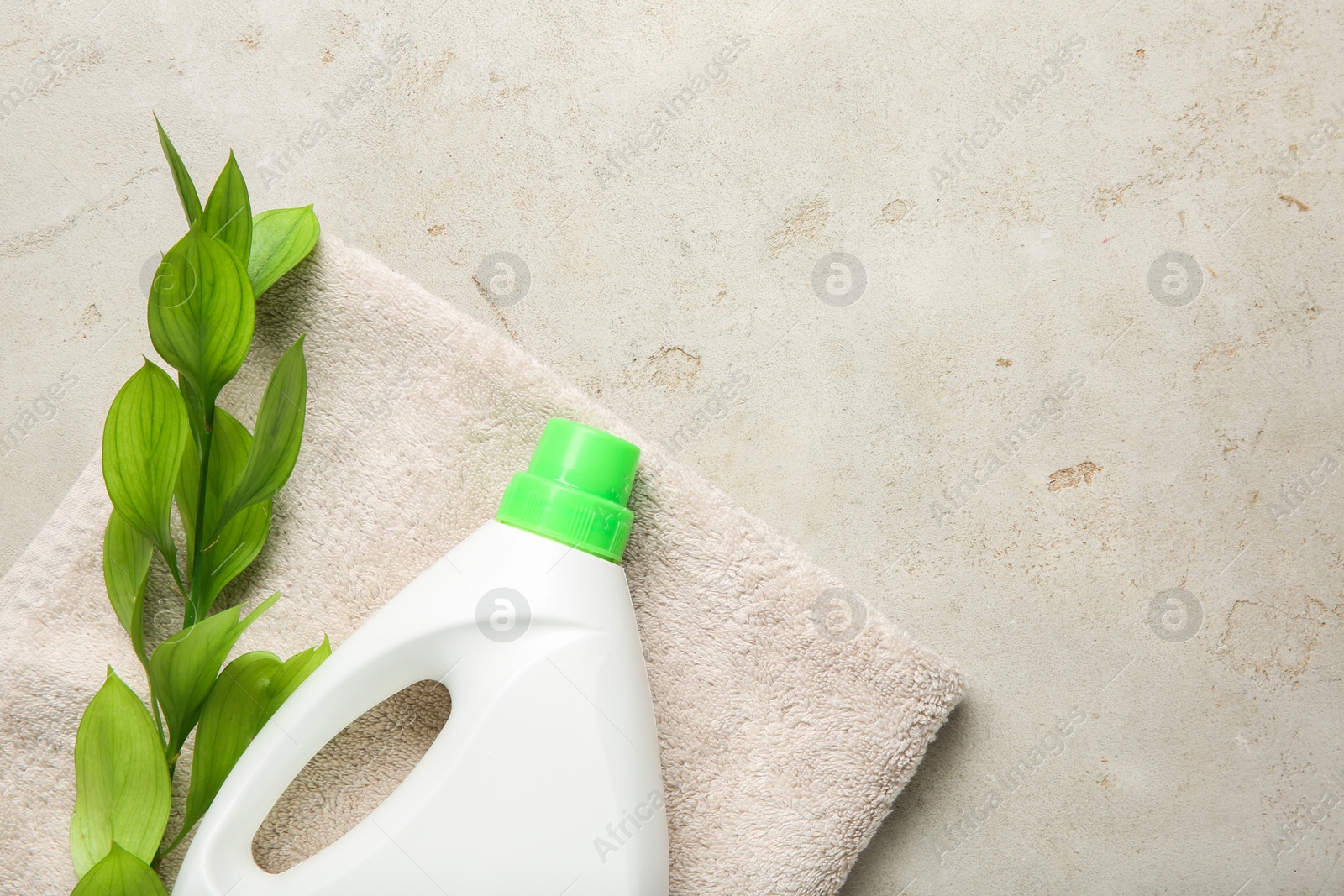 Photo of Laundry detergent in bottle, branch and towel on grey textured table, top view. Space for text