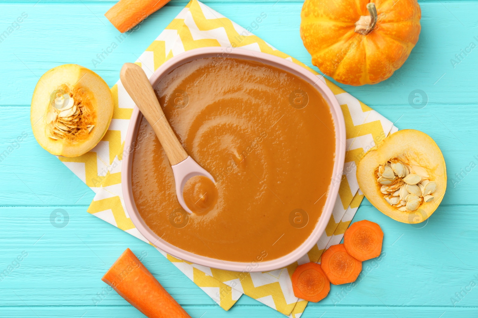 Photo of Delicious baby food in bowl and ingredients on light blue wooden table, flat lay