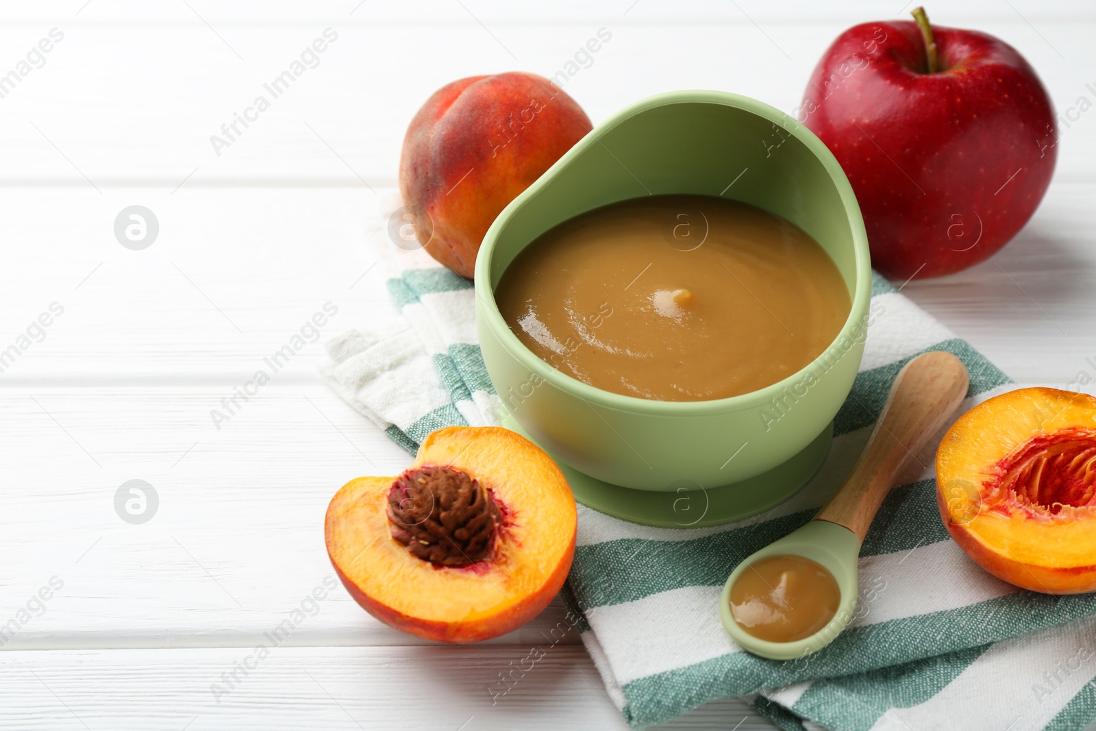 Photo of Delicious baby food in bowl and ingredients on white wooden table. Space for text