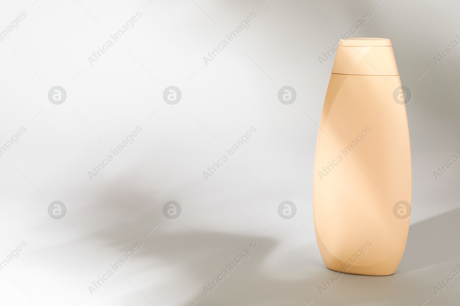 Photo of Shampoo in container on grey background, space for text