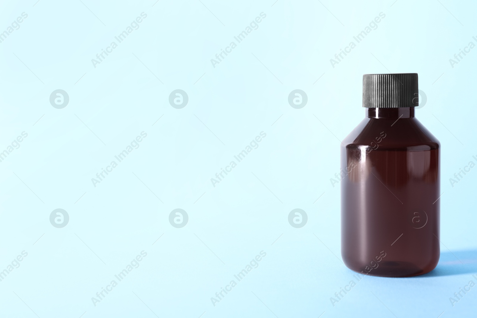 Photo of Shampoo in bottle on light blue background, space for text