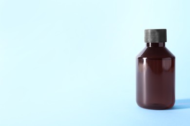 Shampoo in bottle on light blue background, space for text