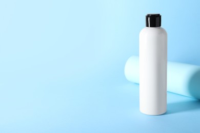 Shampoo in bottle on light blue background, space for text