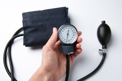 Woman with blood pressure measuring device on light background, top view