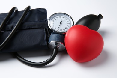 Photo of Blood pressure measuring device and red decorative heart on light background