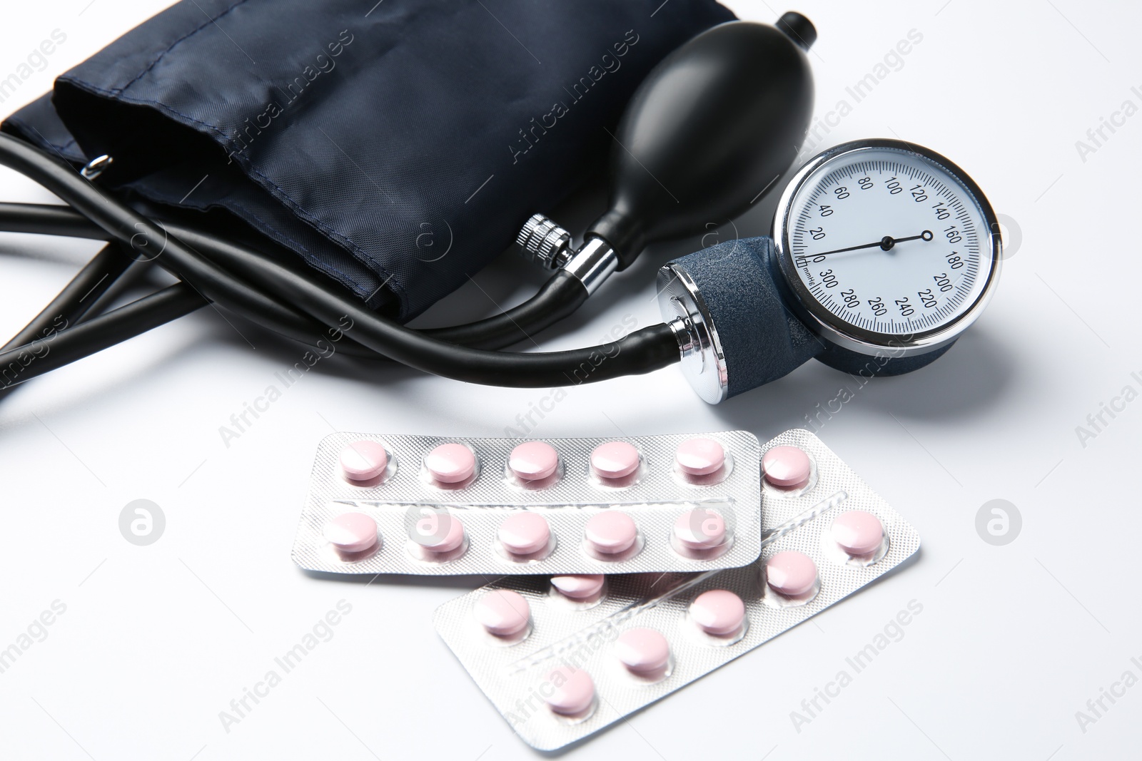 Photo of Blood pressure measuring device and pills in blisters on light background