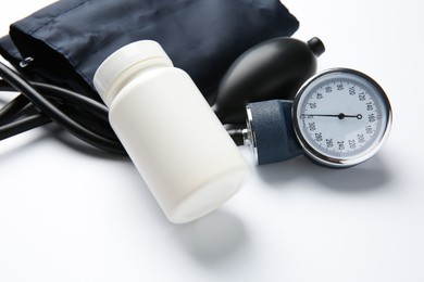 Blood pressure measuring device and jar of pills on light background