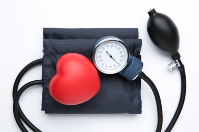 Photo of Blood pressure measuring device and red decorative heart on light background, top view