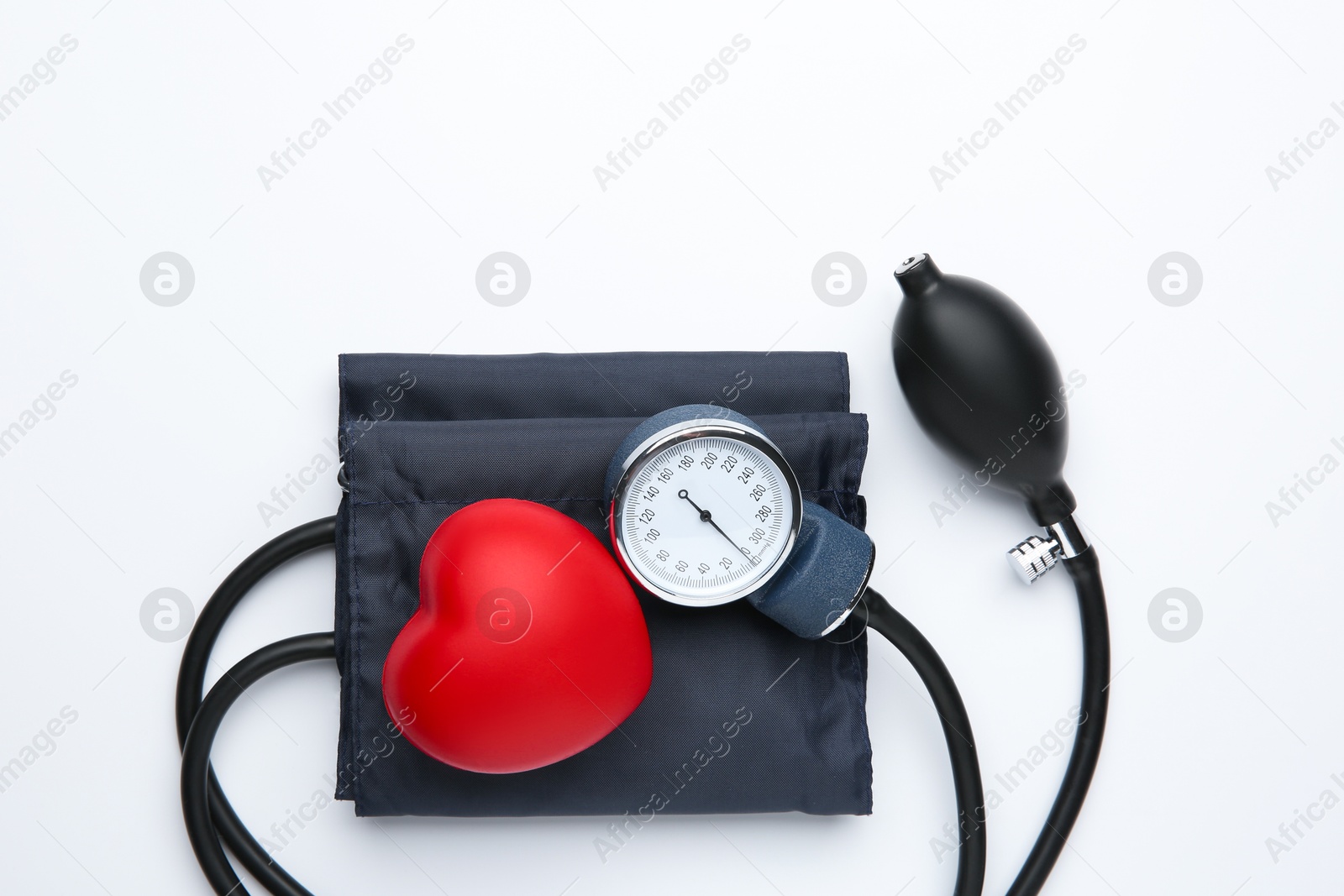 Photo of Blood pressure measuring device and red decorative heart on light background, top view