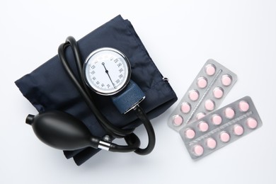 Blood pressure measuring device and pills in blisters on light background, flat lay