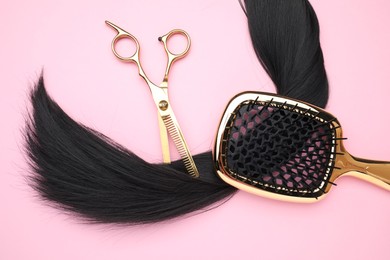 Photo of Black hair strand, brush and professional scissors on pink background, top view