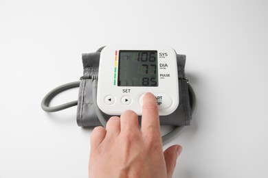 Photo of Man using blood pressure measuring device on white background, closeup