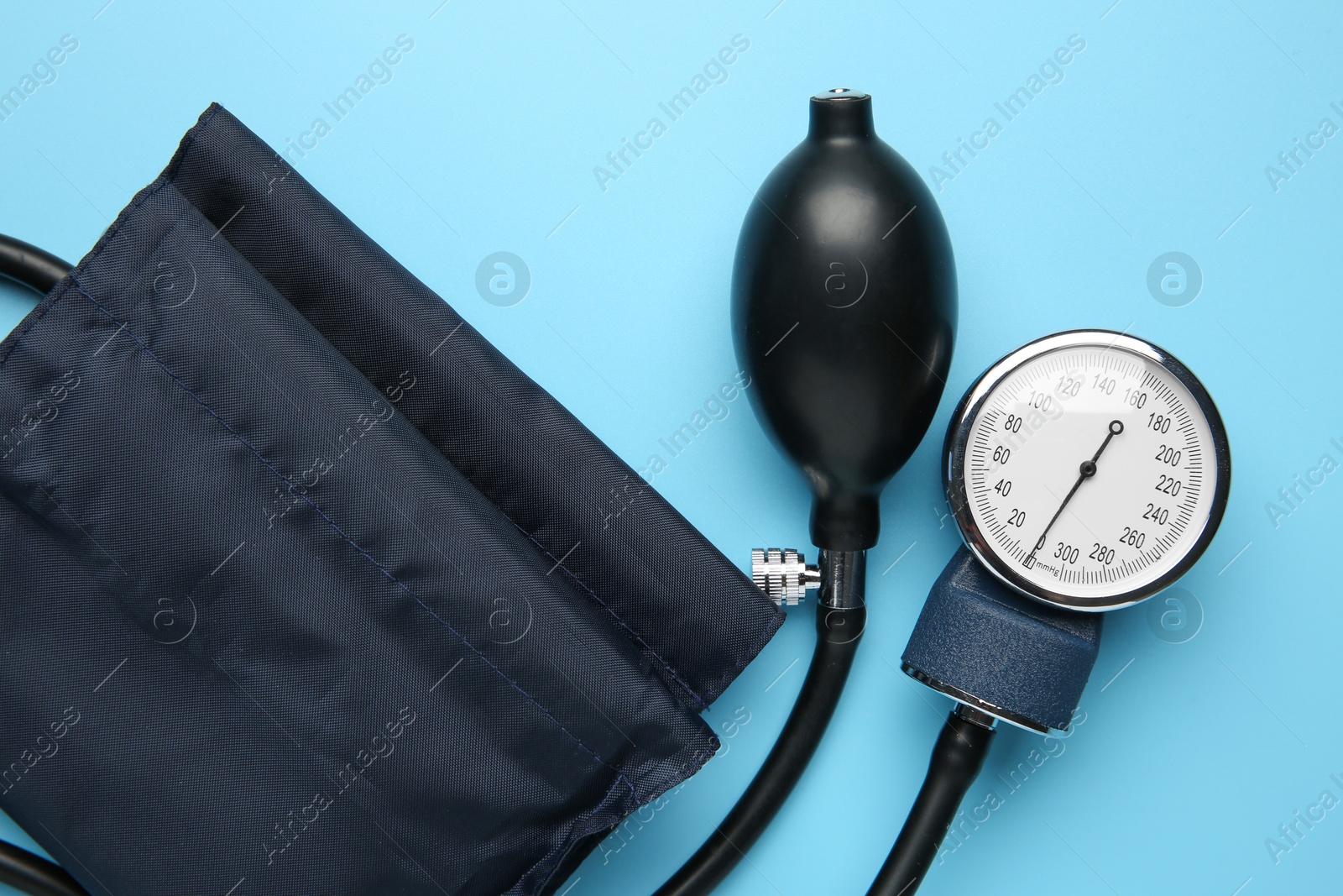 Photo of Blood pressure measuring device on light blue background, top view