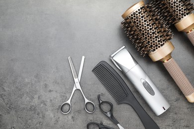 Photo of Professional hair clipper, different combs and scissors on grey surface, flat lay