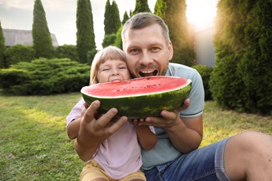 Photo of Man and his cute daughter eating juicy watermelon outdoors together