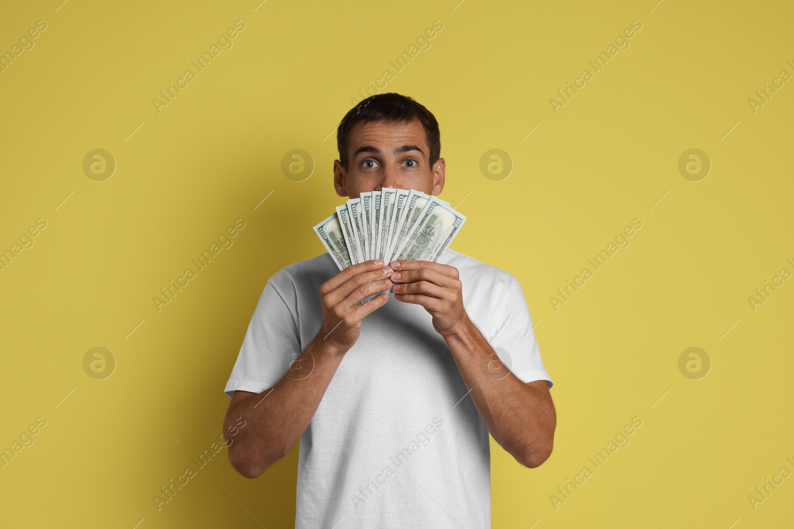 Photo of Man with dollar banknotes on yellow background