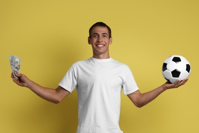 Happy man with money and soccer ball on yellow background