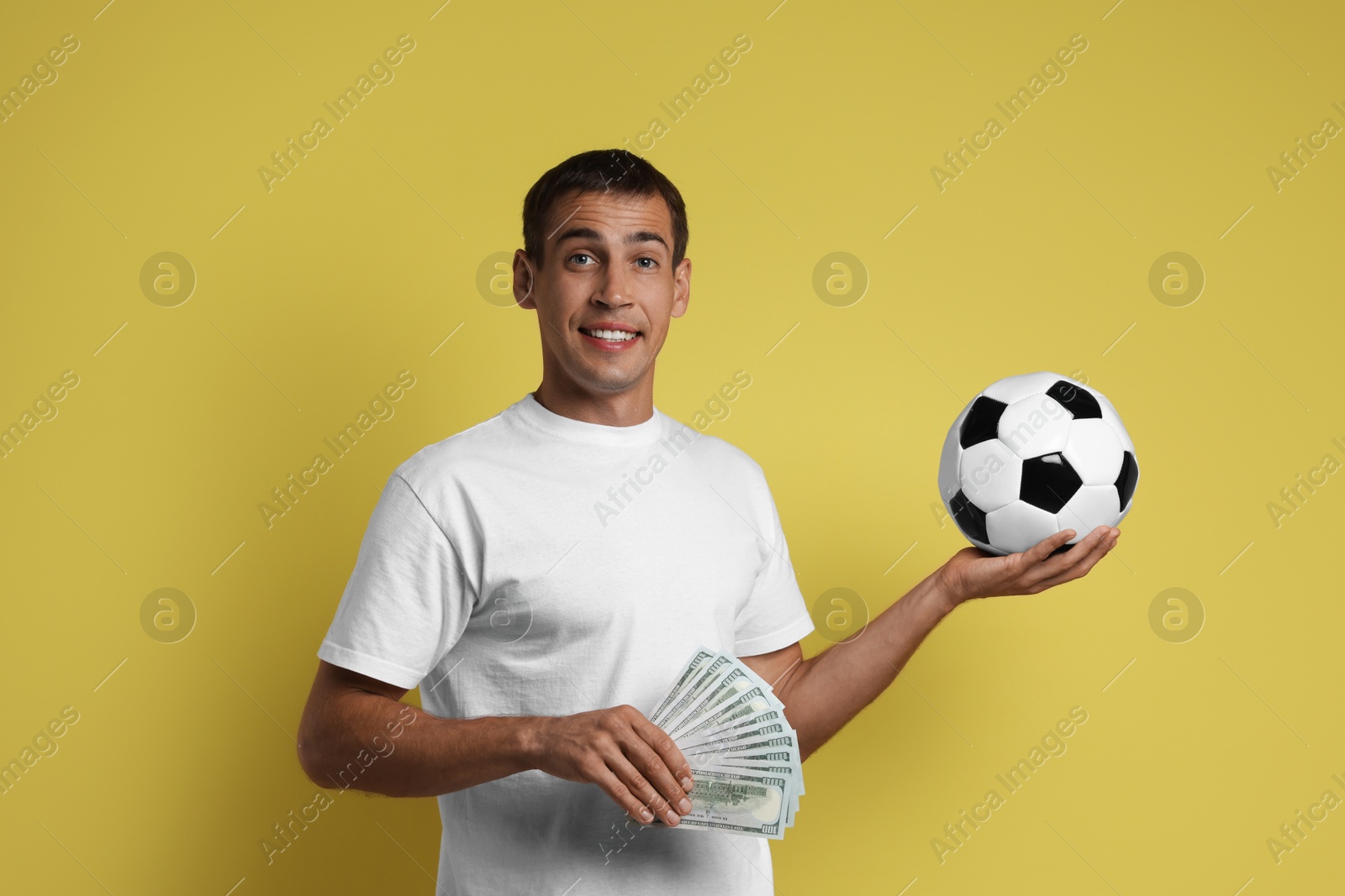 Photo of Happy man with money and soccer ball on yellow background