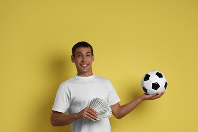 Photo of Happy man with money and soccer ball on yellow background