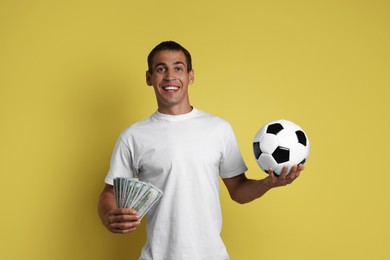 Photo of Happy man with money and soccer ball on yellow background