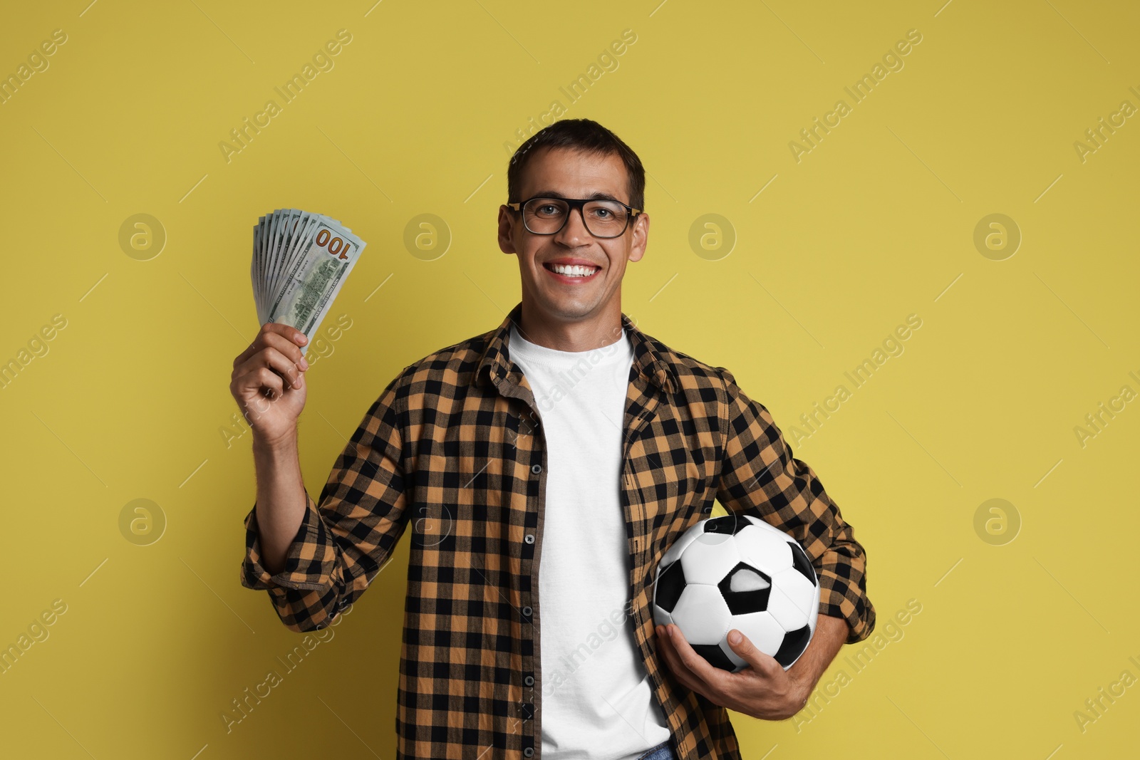 Photo of Happy man with money and soccer ball on yellow background