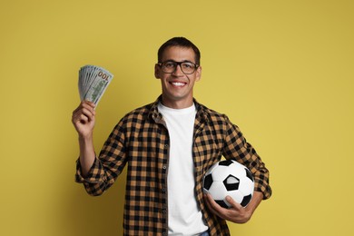 Photo of Happy man with money and soccer ball on yellow background