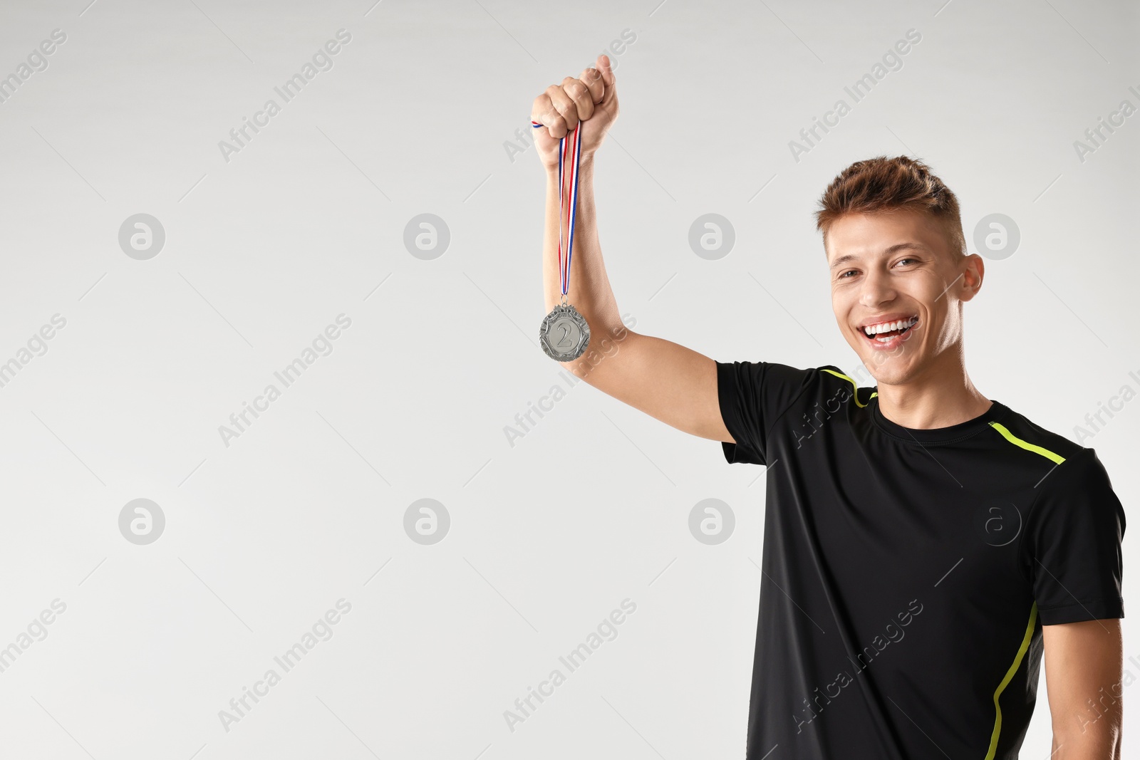 Photo of Happy winner with silver medal on light grey background. Space for text