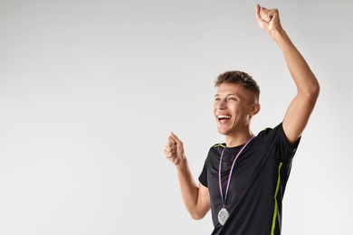 Photo of Happy winner with silver medal on light grey background. Space for text