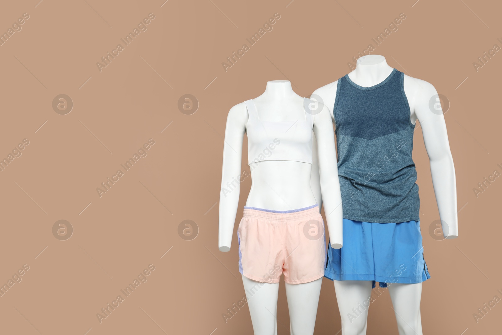 Photo of Female and male mannequins with stylish sportswear on beige background, space for text