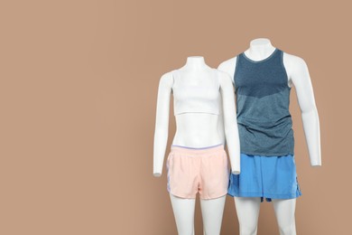 Photo of Female and male mannequins with stylish sportswear on beige background, space for text