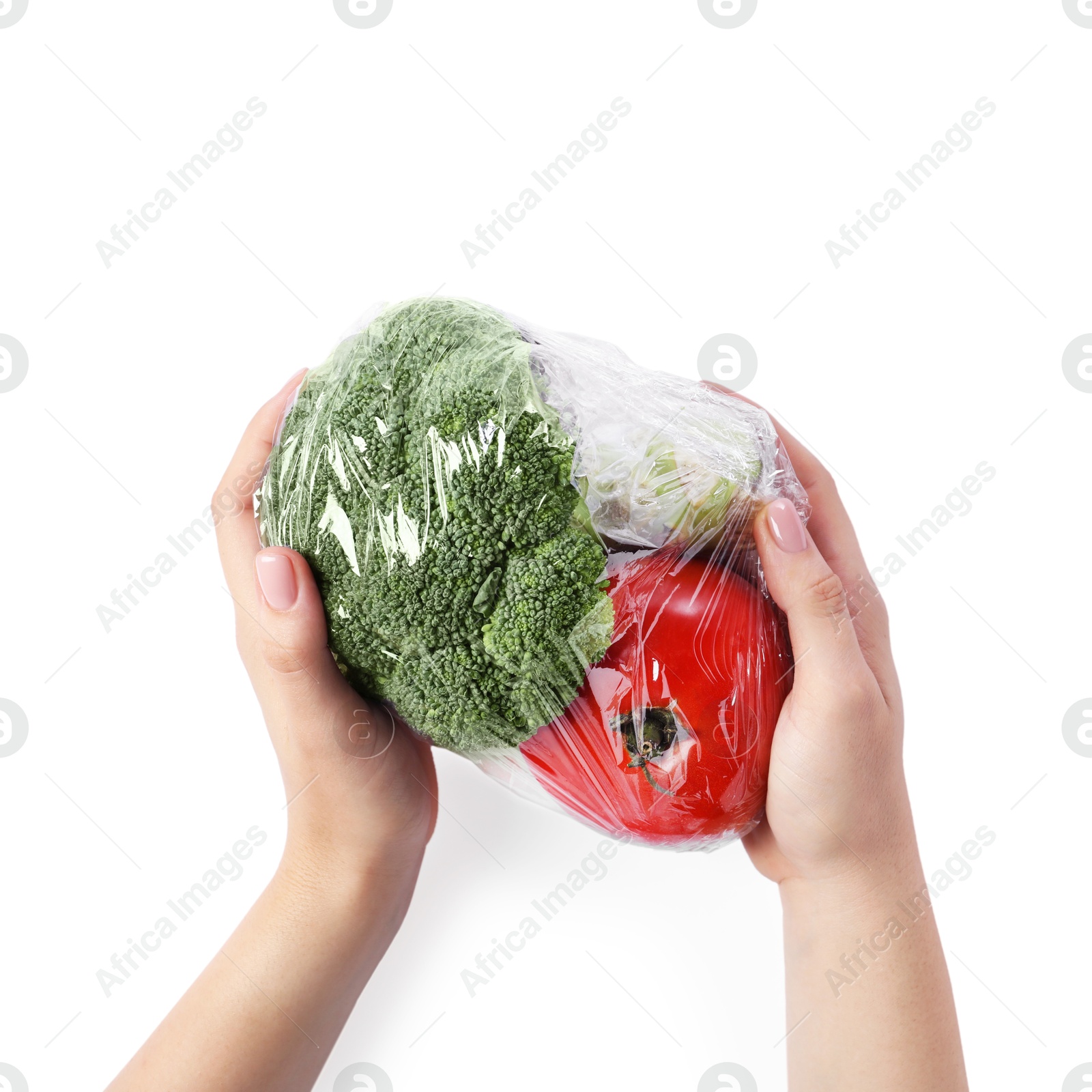 Photo of Woman holding fresh vegetables with plastic food wrap on white background, top view