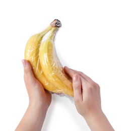 Photo of Woman holding bananas with plastic food wrap on white background, top view