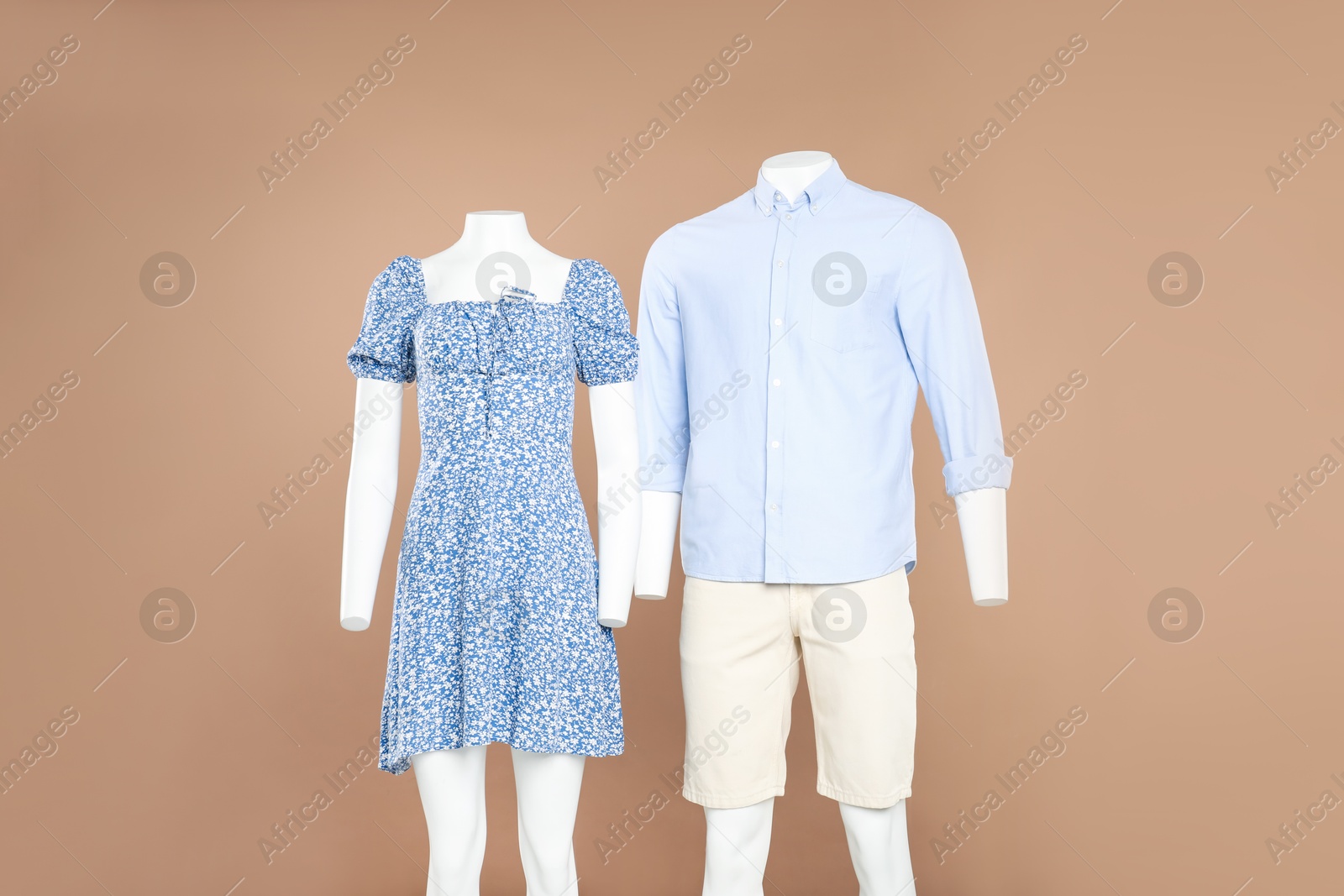 Photo of Female and male mannequins with stylish outfits on light brown background