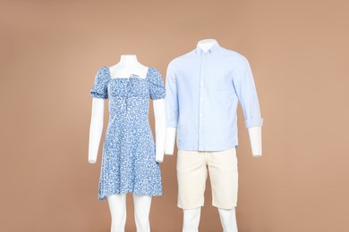 Photo of Female and male mannequins with stylish outfits on light brown background