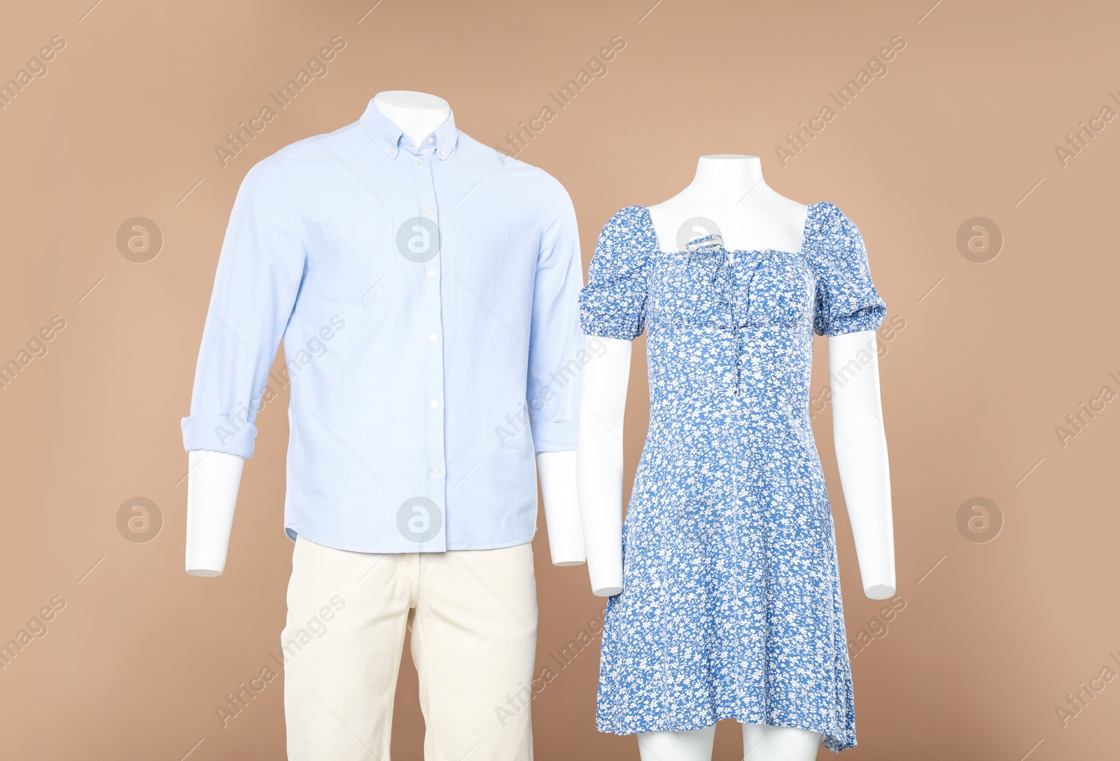 Photo of Female and male mannequins with stylish outfits on light brown background