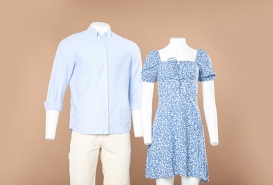 Female and male mannequins with stylish outfits on light brown background