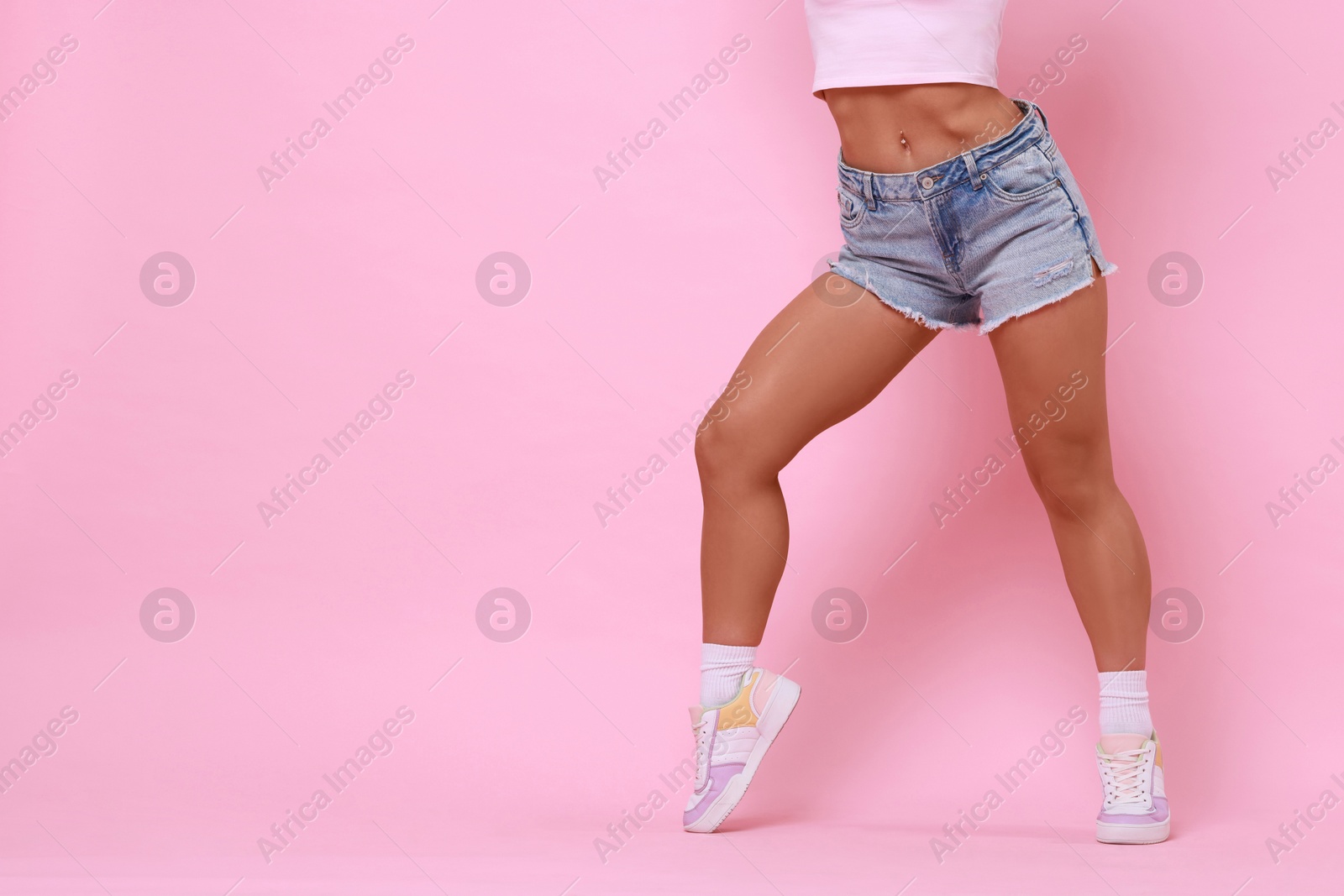 Photo of Woman wearing stylish denim shorts on pink background, closeup. Space for text