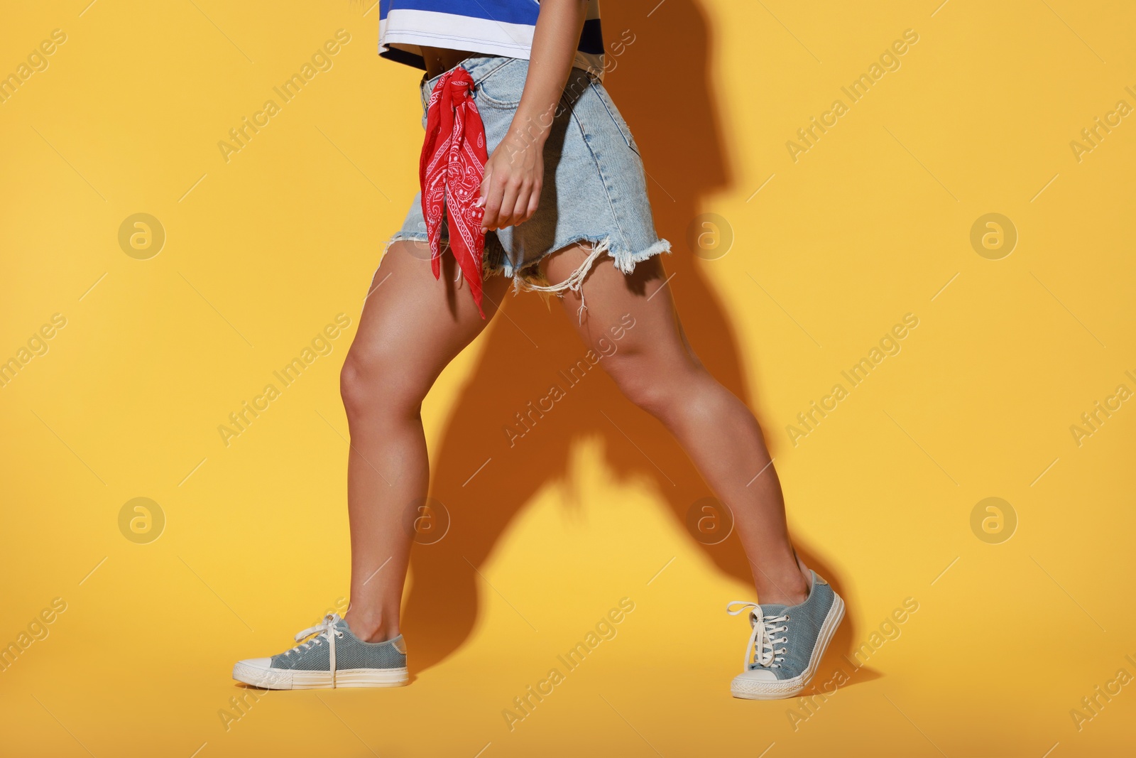 Photo of Woman wearing stylish denim shorts on yellow background, closeup